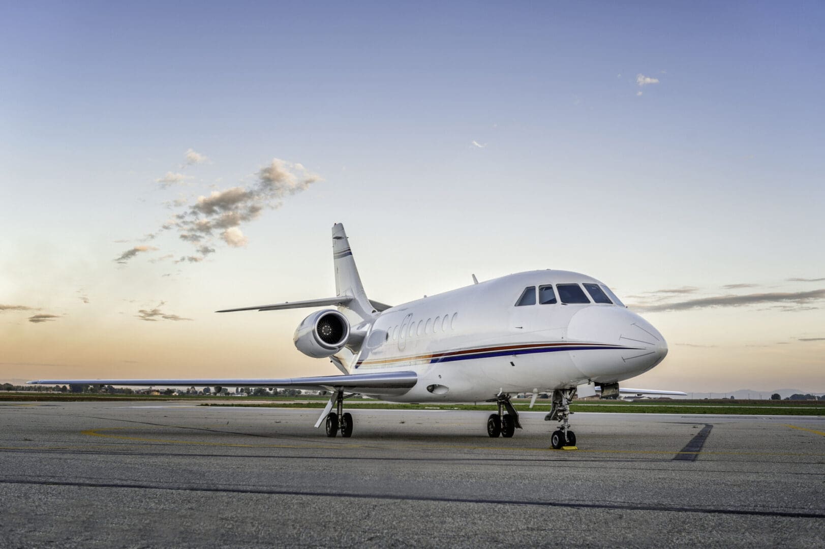 Private jet on airport runway at sunset.