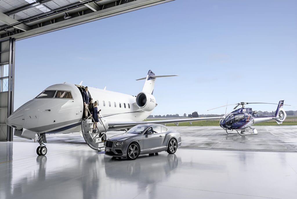 A silver car is parked on the tarmac near an airplane.