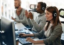 A group of people sitting at computers with headphones on.