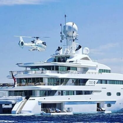 A helicopter flying over a large white boat.